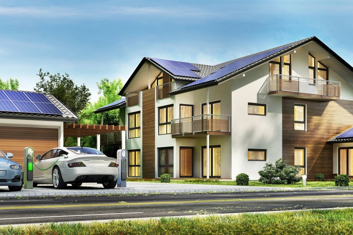 Auf diesem Bild sind ein Eigenheim und eine Garage zu sehen mit Photovoltaik auf dem Dach und E-Autos an einer Wallbox.